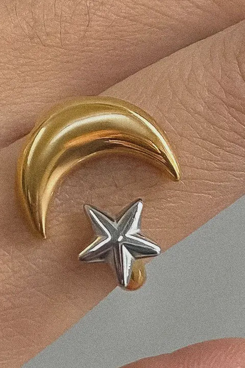 Gold crescent moon and silver star earring on a hand