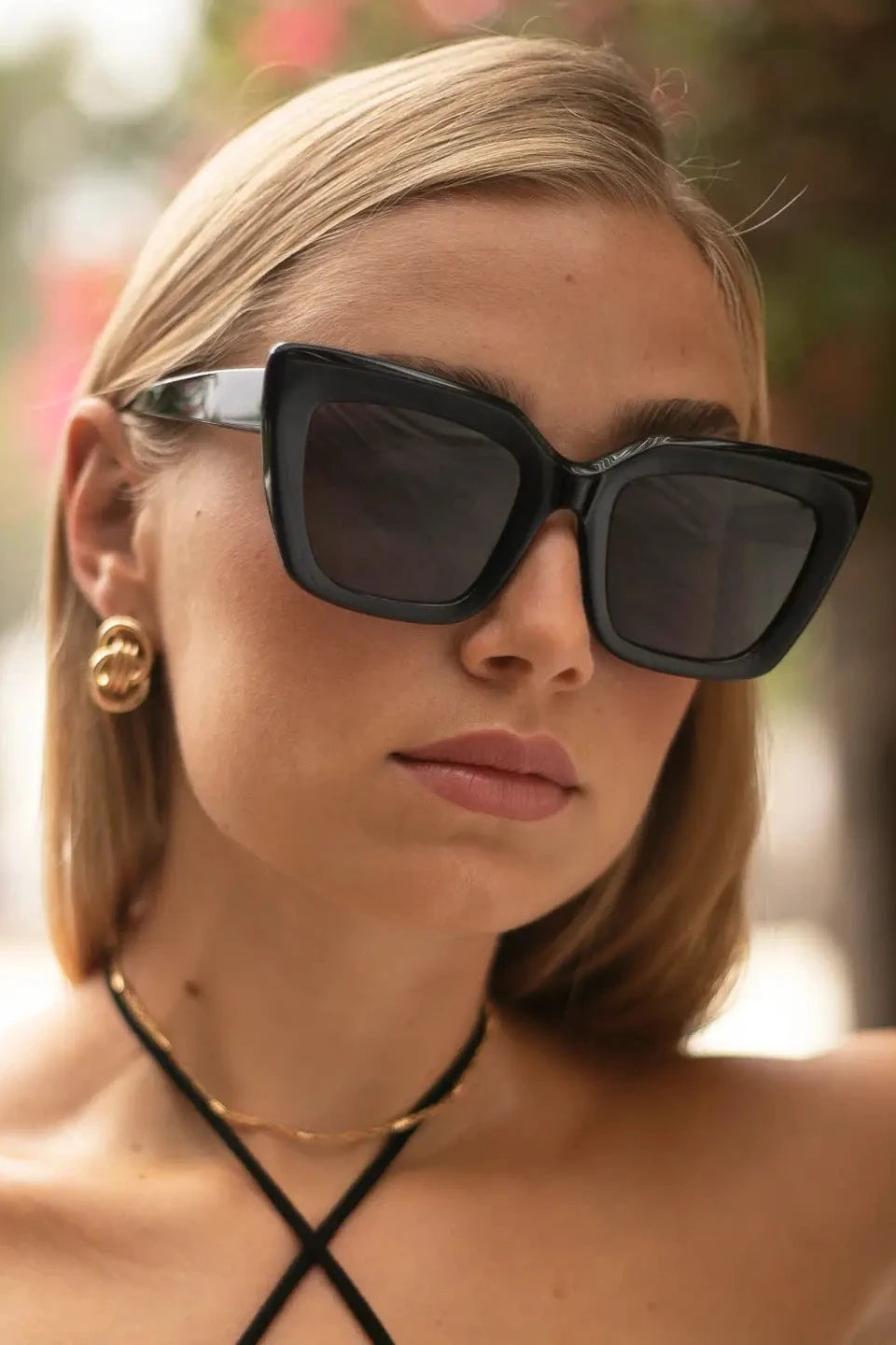 Woman wearing black sunglasses with a blurred outdoor background