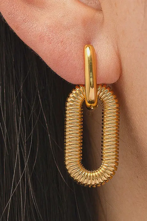 Gold hoop earring worn by a person with black hair.