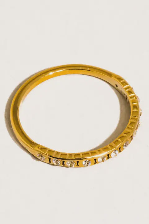Gold ring with small diamonds on a light gray background