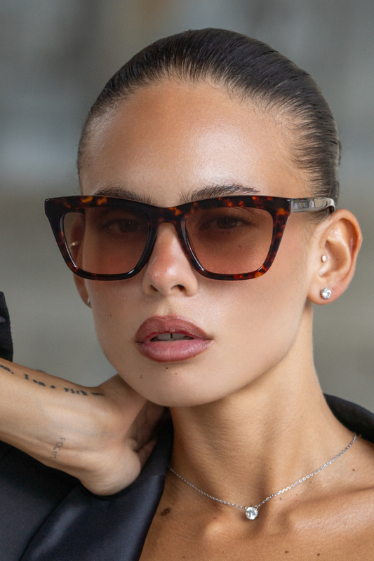 Woman wearing tortoiseshell sunglasses with a blurred background