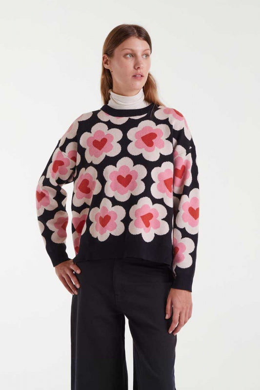 Woman wearing a black sweater with pink floral patterns on a white background