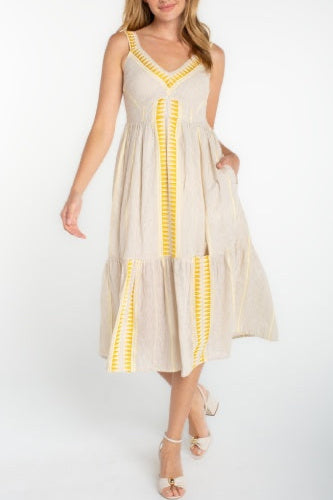 Woman wearing a beige dress with yellow accents on a white background