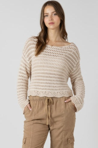 Woman wearing a beige crochet sweater and beige pants on a white background