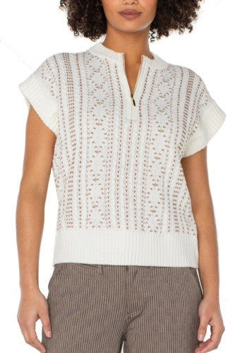 Woman wearing a white lace top with short sleeves and brown pants on a white background