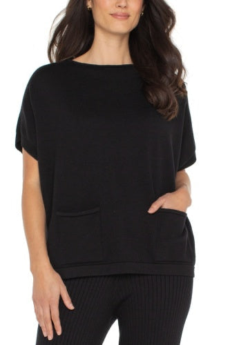 Woman wearing a black oversized top with a plain background