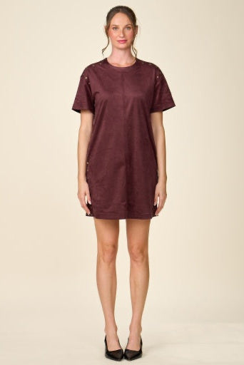 A woman modeling a short-sleeve, crew-neck mini dress in a deep burgundy color, standing against a solid beige studio background.
