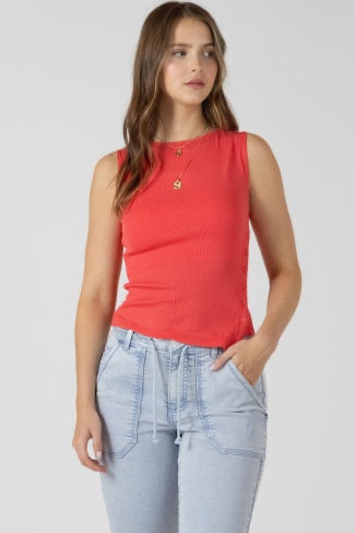 Woman wearing a red sleeveless top and light blue jeans on a plain background