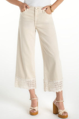 Beige wide-leg pants with lace trim worn by a person on a white background