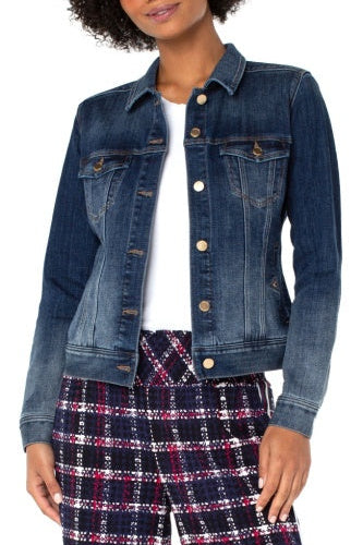 Woman wearing a blue denim jacket over a white shirt and plaid pants on a white background