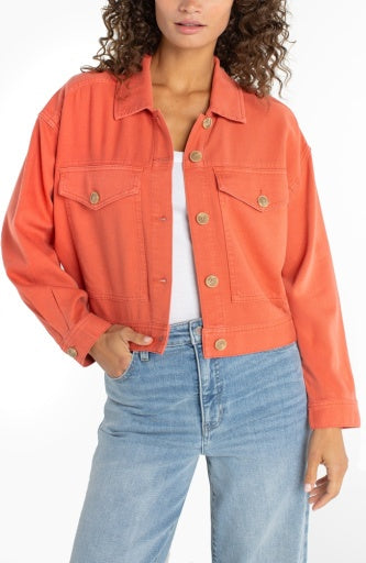 Person wearing an orange denim jacket and light blue jeans on a white background