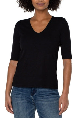 Woman wearing a black V-neck sweater and blue jeans on a white background