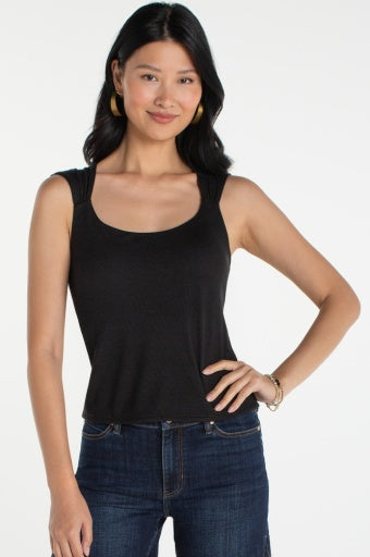 Woman wearing a black tank top and blue jeans on a white background