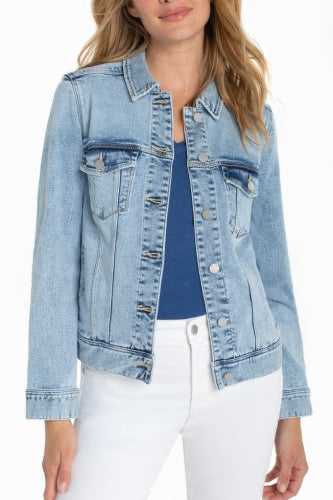 Woman wearing a light blue denim jacket over a blue top and white pants.