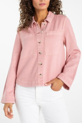 Person wearing a pink denim jacket and white pants on a white background
