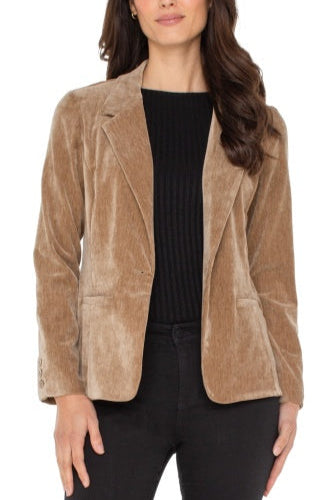Woman wearing a brown corduroy blazer over a black top on a white background