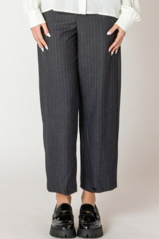 Person wearing gray checkered pants and black shoes on a plain background