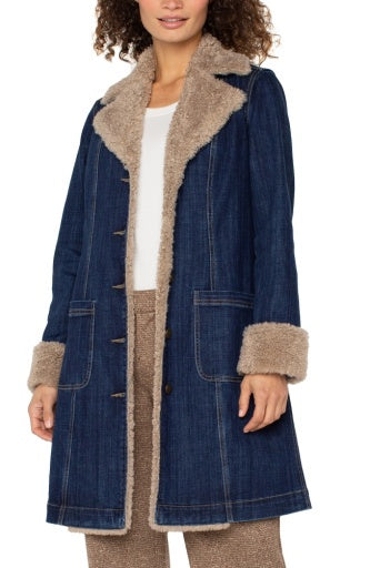 Denim coat with beige fur lining worn by a person on a white background