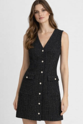 Woman wearing a black sleeveless dress with white buttons on a white background