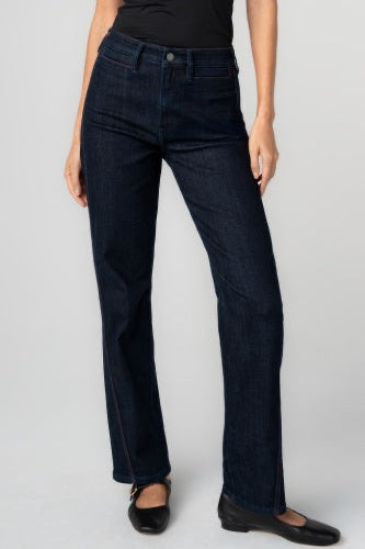 Dark blue jeans worn by a person on a plain background