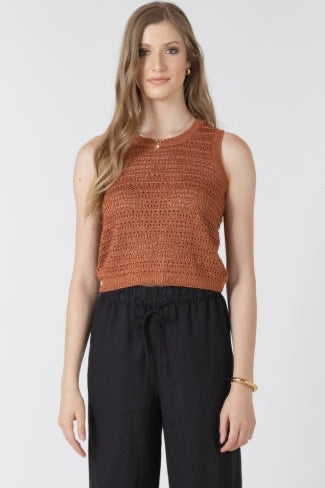 Woman wearing a brown sleeveless top and black pants on a white background
