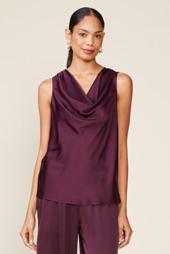 Woman wearing a sleeveless purple top with a draped neckline.
