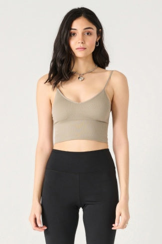 Woman wearing a green ribbed tank top and black leggings on a white background