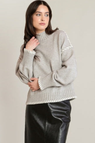 Woman wearing a gray sweater with white trim on a beige background