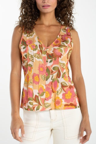 Woman wearing a sleeveless floral top with a white background