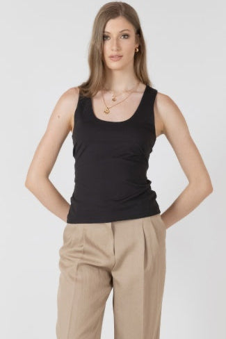 Woman wearing a black tank top and beige pants on a white background