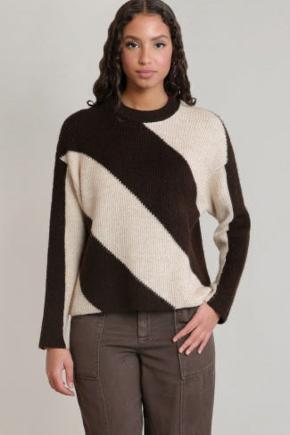 Woman wearing a black and beige sweater with a plain background