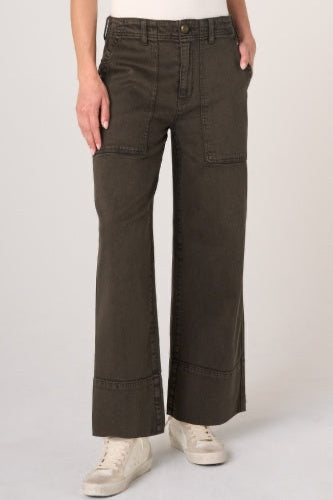 A person wearing dark olive green wide-leg cargo pants with a white top and white sneakers, shown from the waist down against a light gray studio background.