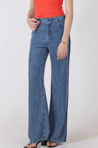 Person wearing blue flared jeans and a red top on a white background