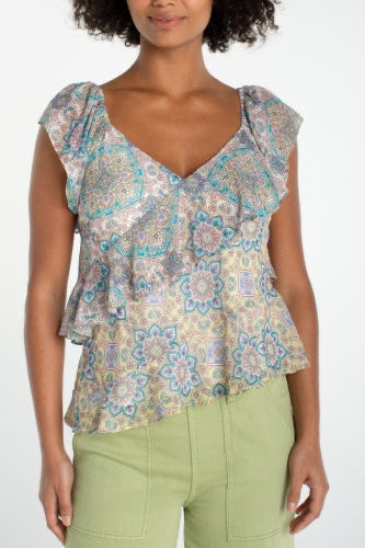 Woman wearing a patterned top and green pants on a white background