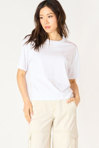 Woman wearing a white t-shirt and beige pants against a plain background