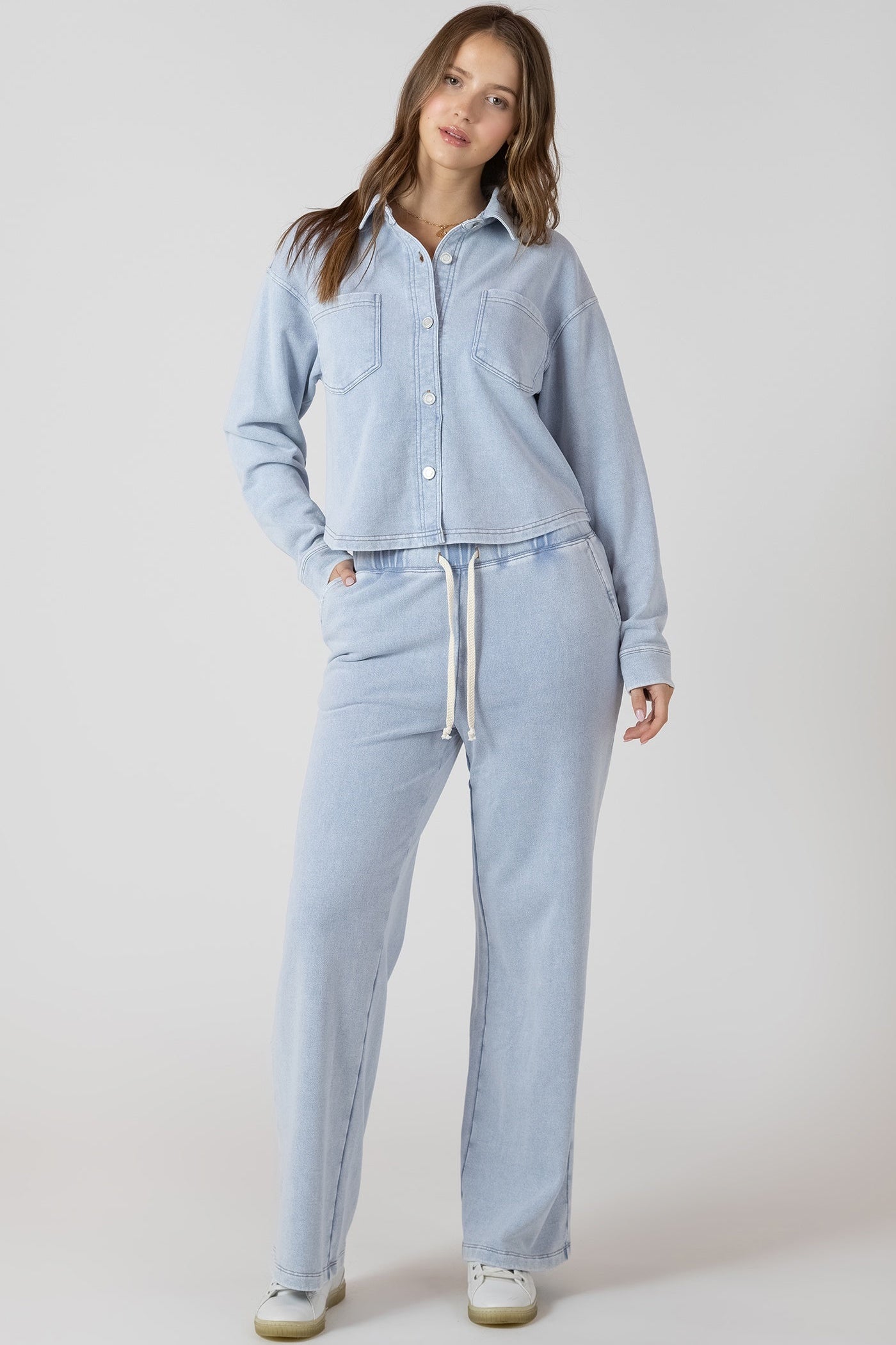 Woman wearing a light blue denim outfit on a plain background