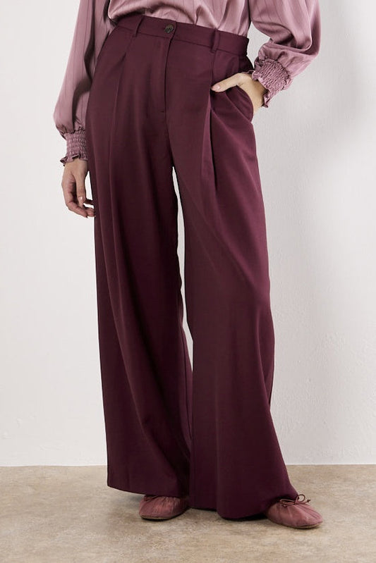 Person wearing maroon wide-leg pants and a matching top against a plain background