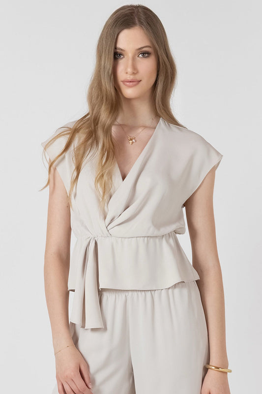 Woman wearing a beige layered top and pants set on a white background